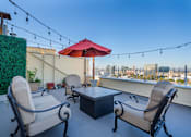 Thumbnail 18 of 25 - A patio with a table, chairs, and a red umbrella.