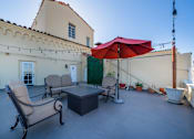 Thumbnail 19 of 25 - A patio with a table, two chairs and an umbrella.