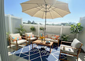 Thumbnail 25 of 35 - A patio with a table, chairs, and an umbrella.