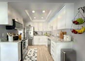 Thumbnail 15 of 35 - A modern kitchen with white cabinets and a black microwave.