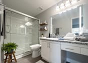 Thumbnail 23 of 35 - A bathroom with a glass shower stall, a toilet, a sink, and a mirror.