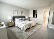 Thumbnail 21 of 35 - A bedroom with a large bed and a nightstand with a lamp.