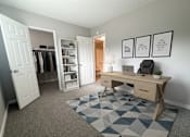 Thumbnail 16 of 35 - A room with a desk, chair, and a rug with a geometric pattern.