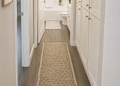 Thumbnail 7 of 20 - A hallway with white walls and a beige rug.