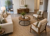 Thumbnail 6 of 20 - A living room with a white couch, a wooden coffee table, and a rug.