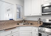 Thumbnail 62 of 67 - A kitchen with white cabinets and a granite countertop.