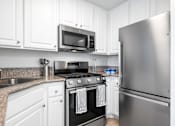 Thumbnail 57 of 67 - A kitchen with a stove, microwave, and refrigerator.