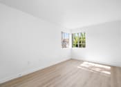 Thumbnail 65 of 67 - A large empty room with a window and wooden flooring.