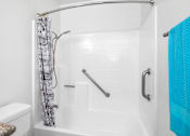 Thumbnail 64 of 67 - A white bathroom with a shower curtain and a blue towel.