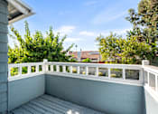 Thumbnail 56 of 67 - A balcony with a white railing and a view of a house and trees.