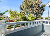 Thumbnail 53 of 67 - A balcony with a white railing and a view of trees and buildings.