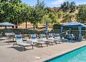 Thumbnail 19 of 67 - A poolside area with chairs and a gazebo.