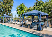 Thumbnail 9 of 67 - A pool area with a blue canopy and lounge chairs.
