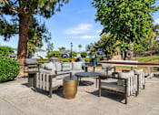 Thumbnail 22 of 67 - A patio seating area with a table and chairs surrounded by trees.
