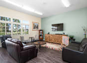 Thumbnail 33 of 67 - A living room with a brown leather couch, a wooden cabinet, and a flat screen TV.