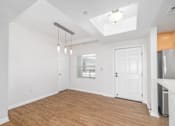 Thumbnail 16 of 49 - A room with white walls and wooden flooring, with a skylight above and a door to the right.
