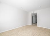 Thumbnail 20 of 49 - A white room with a carpeted floor and a doorway leading to another room.
