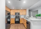 Thumbnail 18 of 49 - A kitchen with wooden cabinets and black appliances.
