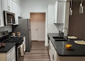 Thumbnail 16 of 23 - A kitchen with black countertops and white cabinets.