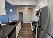 Thumbnail 18 of 23 - A kitchen with a black countertop and stainless steel appliances.