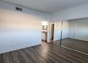 Thumbnail 19 of 23 - A room with wooden floors and a white wall with a doorway leading to another room.
