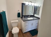 Thumbnail 20 of 23 - A bathroom with a white toilet and a sink with a mirror above it.