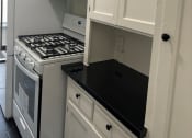 Thumbnail 27 of 35 - a small kitchen with white cabinets and a stove and microwave
