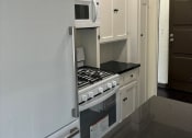 Thumbnail 35 of 35 - a small kitchen with white cabinets and a stove and microwave