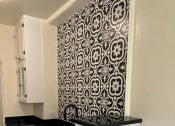 Thumbnail 30 of 35 - a kitchen with black counter tops and white cabinets and a black and white wallpaper