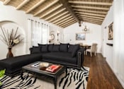 Thumbnail 21 of 27 - Villa Valentino 12 Living Room with a black studded couch and wooden ceiling with a seating area in the back