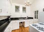Thumbnail 19 of 27 - Villa Valentino 17 Kitchen with small chandelier and black granite counter and white cabinets and a small stove