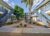 Thumbnail 4 of 4 - courtyard with benches and trees at the whispering winds apartments in pearland, tx
