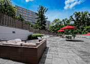 Thumbnail 3 of 15 - A patio with a red umbrella and a stone wall.