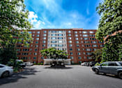 Thumbnail 1 of 15 - A large red brick building with a parking lot in front.