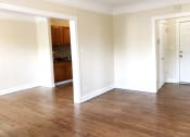 Thumbnail 37 of 38 - an empty living room with hardwood floors and a kitchen in the background