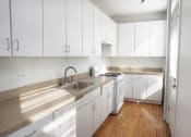 Thumbnail 31 of 48 - a kitchen with white cabinets and a wooden floor