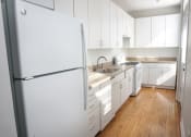 Thumbnail 33 of 48 - a kitchen with white cabinets and a wooden floor
