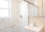 Thumbnail 25 of 38 - a bathroom with a white sink and a shower with a glass door