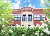 Thumbnail 39 of 48 - the front of a brick building with trees and flowers