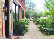 Thumbnail 44 of 48 - a sidewalk lined with bushes and trees in front of a building