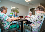 Thumbnail 108 of 109 - Four elderly women sitting around a table playing a game.
