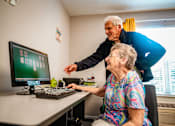 Thumbnail 94 of 109 - A man is helping an elderly woman with her computer.