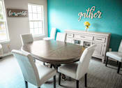 Thumbnail 59 of 109 - A dining room with a table and chairs and a wall decal that says "gather".