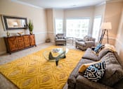 Thumbnail 86 of 109 - A living room with a yellow rug and a glass coffee table.
