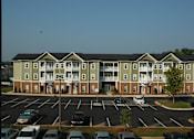 Thumbnail 81 of 109 - A large apartment complex with a parking lot in front.