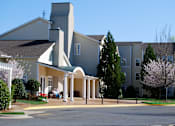 Thumbnail 73 of 109 - A church with a green roof and a white steeple is surrounded by a parking lot.
