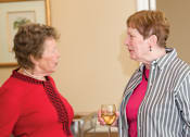 Thumbnail 104 of 109 - Two women are having a conversation while holding wine glasses.