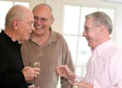 Thumbnail 106 of 109 - Three men are laughing and talking while holding drinks.
