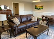 Thumbnail 69 of 109 - A brown leather couch with a remote on the coffee table.