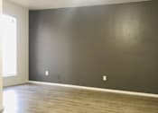 Thumbnail 5 of 7 - an empty living room with a gray wall and wood floors at Archer Village Apartments,Sherman, TX, 75092